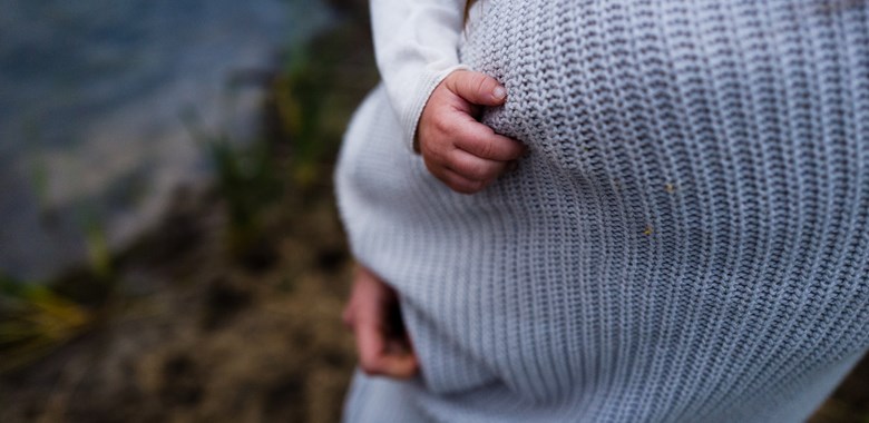 Mamma/förälder håller i sitt barn som har greppat tag i tröjan